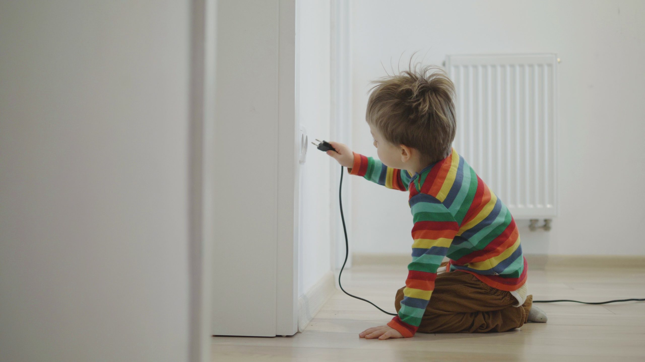 Ensuring Child Safety with Tamper Resistant Devices: A Must for Every Home - Picture of child near outlet holding plug
