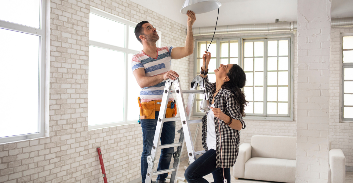 Man standing on ladder and woman helping with electrical upgrades